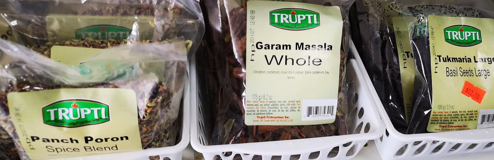 Trupti brand whole spices including Garam Masala, Panch Poron, and Tukmaria basil seeds on store shelf