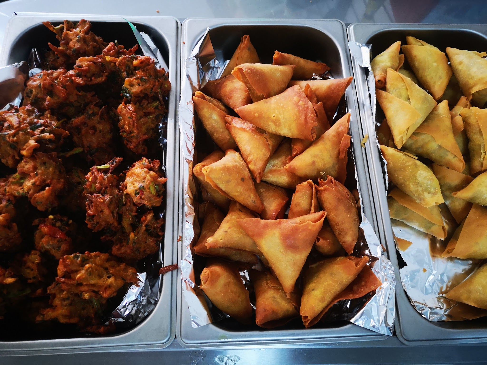 Freshly made samosas and pakoras in serving trays at the Goodies On Mews hot food counter